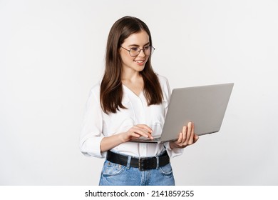 Portrait of young office woman, entrepreneur answer clients on laptop, working with computer with happy face, standing over white background