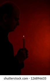 Portrait Of Young Pastor Holding Candle In His Hand, Isolated On Black