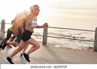 Portrait Of Young People Running On Seaside Promenade. Group Of Women Running Marathon.