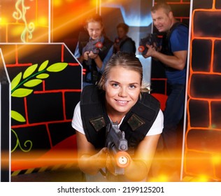 Portrait Of Young Positive Woman With Laser Gun Having Fun With Family On Lasertag Arena