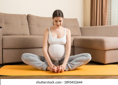 Portrait of young pregnant yoga model working at the home. Pregnancy Yoga and Fitness concept at coronavirus time.