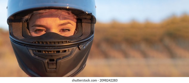 Portrait Of A Young Pretty Blonde Biker Woman Looking At Camera With Motorcycle Safety Helmet. Pretty Eyes Made Up. Copy Space