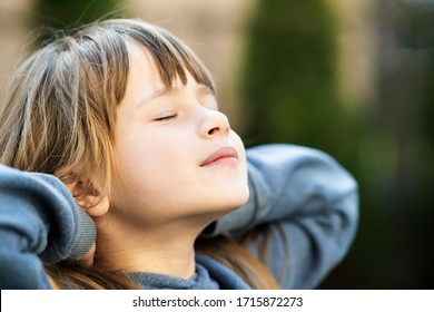 Portrait Of Young Pretty Child Girl With Long Hair Enjoying Warm Sunny Day In Summer Outdoors. Cute Female Kid Relaxing On Fresh Air Outside.