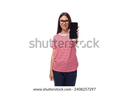 portrait of a young pretty european brunette woman dressed in a summer striped t-shirt with a smartphone in her hand on a white background
