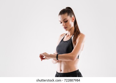Portrait Of A Young Pretty Fitness Woman Looking At Her Wrist Watch Isolated Over White Background