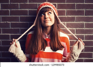 Portrait of young pretty funny smiling girl in cold weather dressed in color clothes and warm hat. Young happy woman having fun outdoor