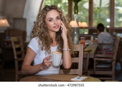 Portrait of young pretty girl with coffee or cappuccino in restaurant 