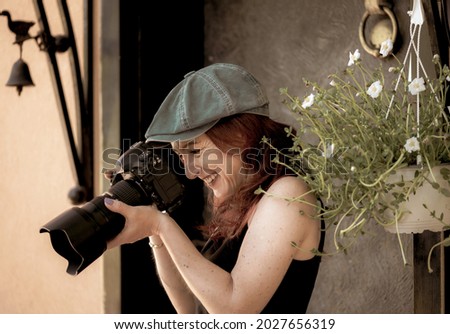 Portrait of a young pretty woman with a camera looking at a funny frame