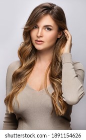 Portrait of young pretty woman with a curly hairstyle on gray background