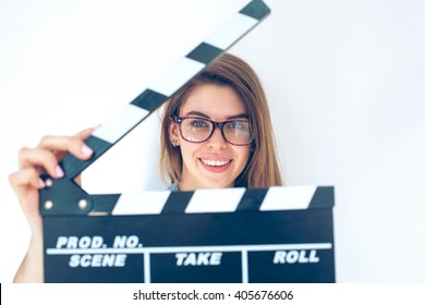 Portrait Of Young Pretty Woman In Glasses With Clapperboard. Film Production And Movie Making Concept