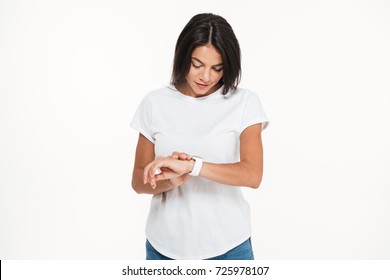 Portrait of a young pretty woman looking at smart watch isolated over white background - Powered by Shutterstock