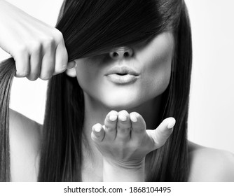 Portrait of young pretty woman model with silky long straight hair holding strand and sending air kiss over white background. Hairstyle, hairsalon, hairdresser, fashion concept