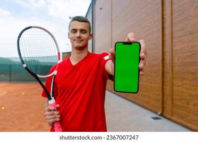 portrait of young professional tennis player after training tennis court with racket in hands shows phone with green screen - Powered by Shutterstock