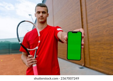 portrait of young professional tennis player after training tennis court with racket in hands shows phone with green screen - Powered by Shutterstock