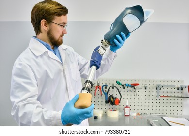 Portrait of young  prosthetics technician holding prosthetic leg  checking it for quality and making adjustments while working in modern laboratory, copy space - Shutterstock ID 793380721