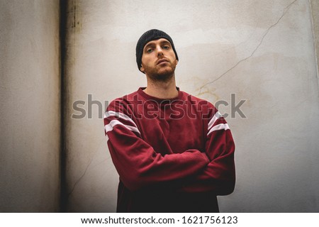 portrait of young rapper posing in front of a white wall in the suburbs