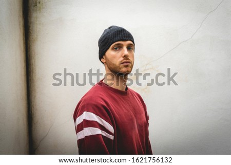 portrait of young rapper posing in front of a white wall in the suburbs