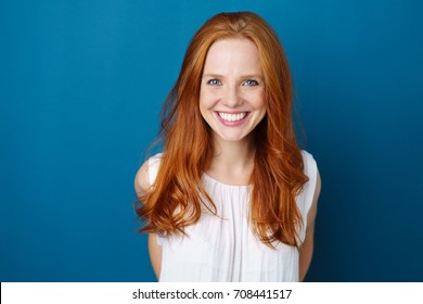 Portrait Of Young Red-haired Smiling Woman Against Blue Background