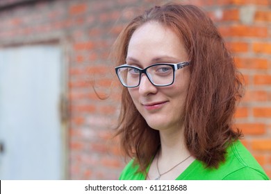 Portrait of a young red-haired woman in green t-shirt standing by the brick wall - Powered by Shutterstock