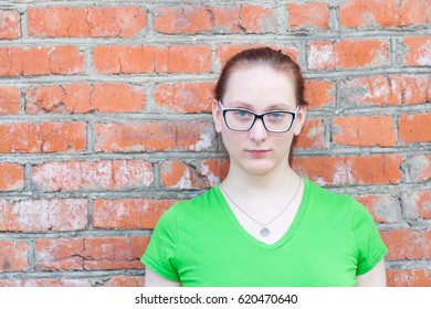 Portrait of a young red-haired woman in green t-shirt standing by the brick wall - Powered by Shutterstock