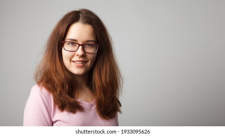 Portrait of young red-haired woman wearing glasses. Head and shoulders portrait.