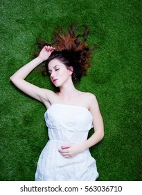 Portrait Of A Young Redhead Woman Lying Down On Green Spring Grass, Above Point Of View 