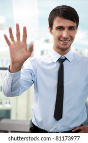 Portrait Of Young Relaxed Business Man Waving Hand To Camera