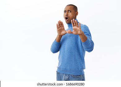 Portrait Of Young Reluctant Nervous African-american Man Telling Stay Away From Me, Making Block With Raised Hands, Stop Gesture, Step Back From Person, Refusing, White Background