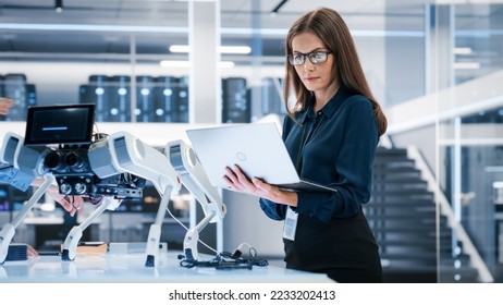 Portrait of a Young Robotics Engineer Using Laptop Computer, Analyzing Robotic Machine Concept in a High Tech Factory. Female Scientist Manipulate and Program the Robot for Work. - Shutterstock ID 2233202413