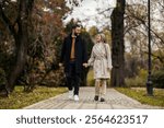 Portrait of young romantic couple walking in city park on date.