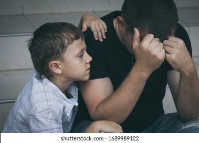 Portrait of young sad little boy and father sitting outdoors at the day time. Concept of sorrow. - Shutterstock ID 1689989122