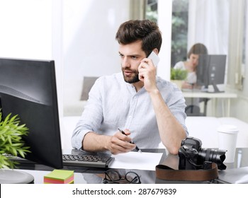 Portrait Of Young Sales Man Making Call While Sitting At Office And Working Online With Computer.