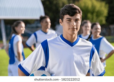 Portrait of young satisfied soccer player holding a football and looking at camera. Young man during training on soccer field. Proud teen guy training on soccer field with school teammates. - Powered by Shutterstock