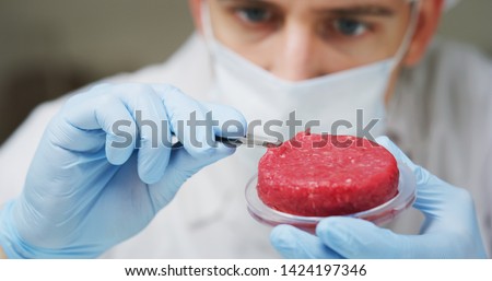 Portrait of an young scientist is inspecting and analyzing with tweezers the cultured artificial meat sample in laboratory.