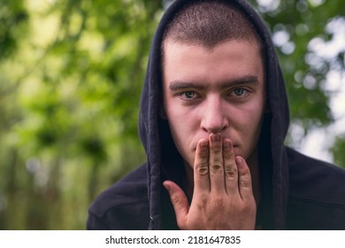 portrait of young serious man wearing hoodie and hand over mouth
