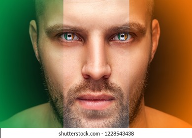 Portrait of a young serious man, in whose eyes the reflected national flag of Ireland, against an isolated black background and flag