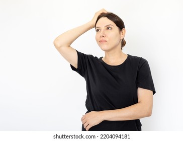 Portrait Of Young Serious Woman In Black T-shirt Looking Up. Female Model Thinking Hard Holding Hand On Head Pondering Over Tough Questions. Portrait, Studio Shot, Pondering Concept