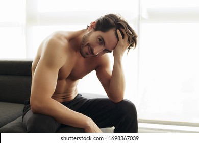 Portrait Of Young Shirtless White Man With Beautiful Hair Is Smiling And Looking At The Camera. Athletic And Muscular Caucasian Male With Fingers Through His Hair Looking Confident