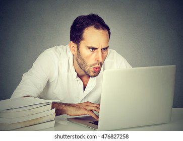 Portrait Young Shocked Business Man Sitting In Front Of Laptop Computer Looking At Screen Isolated Grey Wall Background. Funny Face Expression Emotion Feelings Problem Perception Reaction