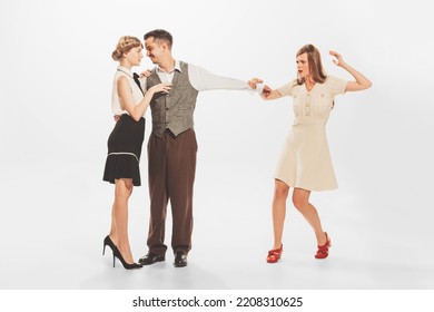 Portrait Of Young Shocked Woman Catching Her Man Flirting And Dancing With Another Girl. Unfaithfulness In Relationship. Concept Of Retro Fashion, Style, Youth Culture, Emotions, Party, Ad