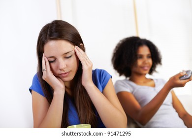 Portrait Of A Young Sick Woman And Other One In The Background Watching TV.