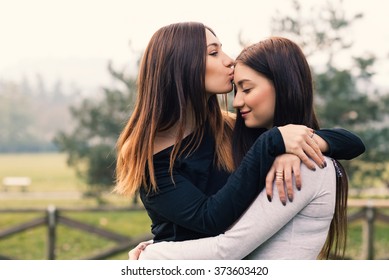 Portrait of young sisters hugging and kissing outdoors in a park.  - Shutterstock ID 373603420