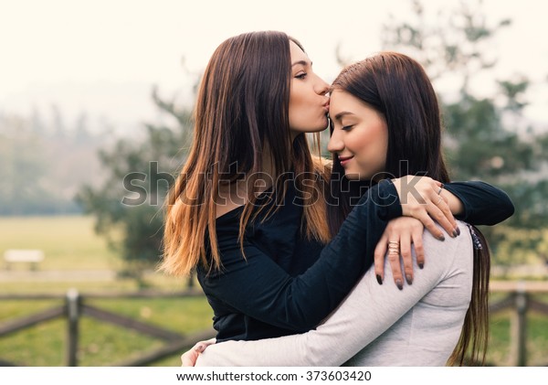 公園の外で抱き合ったりキスをしたりする姉妹のポートレート の写真素材 今すぐ編集