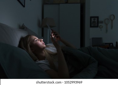 Portrait Of Young Sleepy Exhausted Woman Lying In Bed Using Smartphone At Late Night, Can Not Sleep.Insomnia, Nomophobia, Sleep Disorder Concept. Dependency On A Cell Phone, Loneliness Crisis