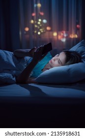 Portrait Of Young Sleepy Woman Lying In Bed Using Smartphone At Late Night, Can Not Sleep. Insomnia, Sleep Disorder Concept.