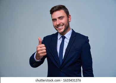 Portrait young smiling businessman. Caucasian guy business suit tie studio gray background. Modern business person Showing thumbs up sign. Portrait of charming successful happy entrepreneur - Powered by Shutterstock