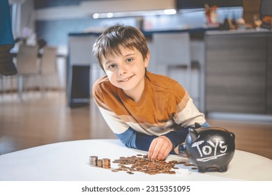 Portrait of a young, smiling, caucasian kid sitting by a living room coffee table, counting his saved up money.  - Powered by Shutterstock