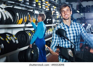 Portrait of young  smiling customer choosing new motorbike in workshop