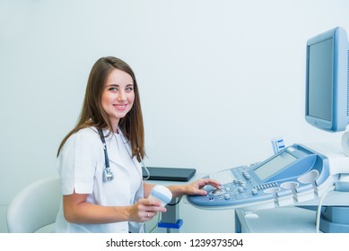 Portrait of young smiling doctor, ultrasound specialist looking at camera and using Ultrasound Scanning Machine for pacient testing. Copy space. Selective focus