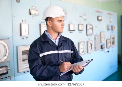 Portrait Of Young Smiling Engineer Taking Notes In Control Room